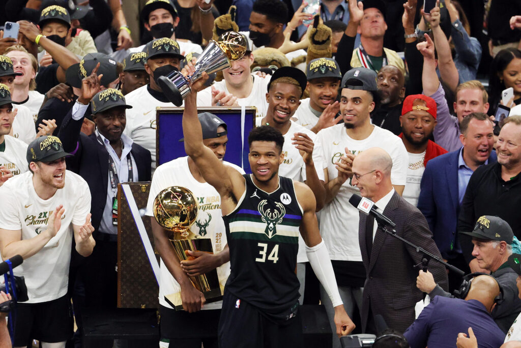 Photo of Giannis Antetokounmpo of the Milwaukee Bucks basketball team holding the Bill Russell NBA Finals MVP award trophy in July 2021.