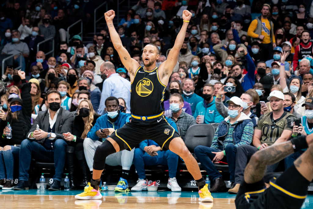 Stephen Curry #30 reacts after Gary Payton II #0 of the Golden State Warriors makes a shot while being fouled during the third quarter during their game against the Charlotte Hornets at Spectrum Center on November 14, 2021 in Charlotte, North Carolina. 